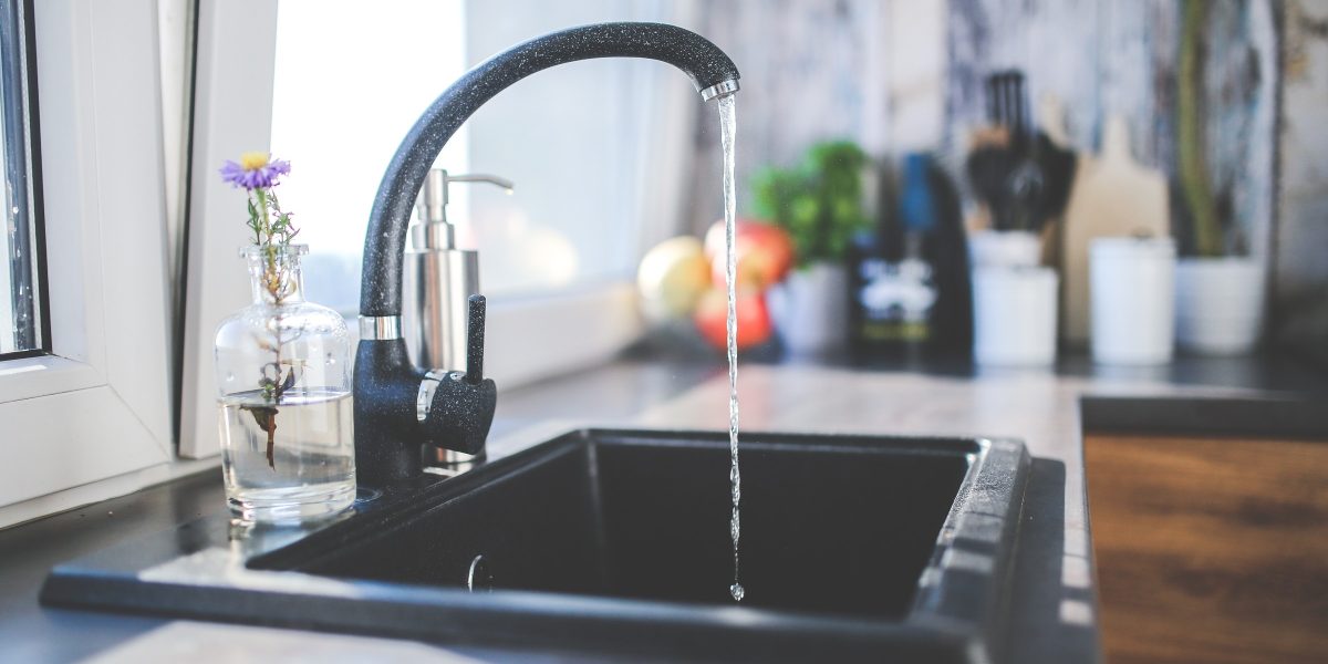 Mitigeur de cuisine noir laissant couler un filet d'eau dans l'évier